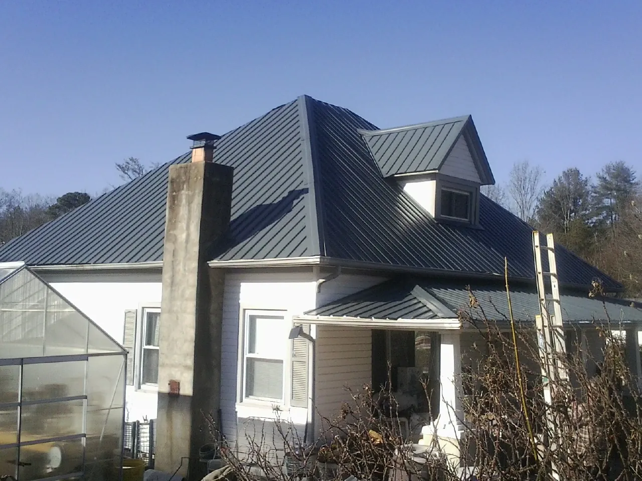 Dark blue standing seam metal roof on a white farmhouse with dormer — Slate & Tile Roof Repair by Roofing Brothers in Medinah