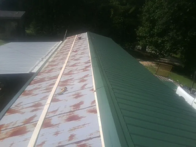 Old rusted panels beside newly installed green metal roofing — Wind Damage Roof Repair by Roofing Brothers in Medinah
