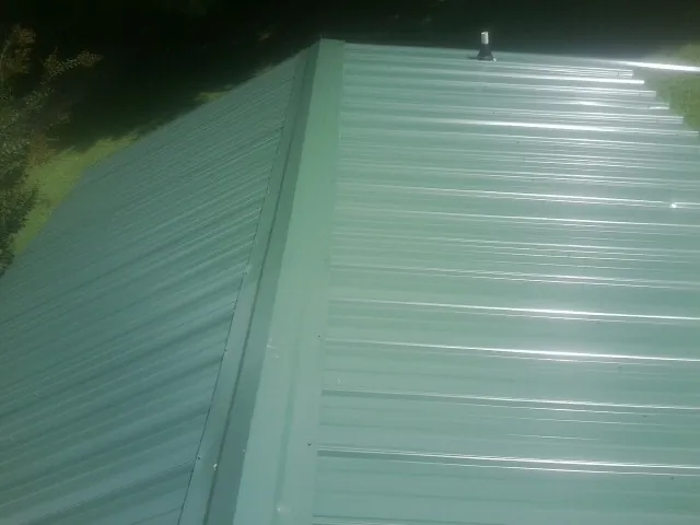 New green metal panels meeting at the ridge of a roof — Flat Roof Repair work by our crew in Medinah