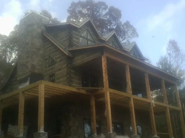 Stone chimney and dormers on a large log home with a timber porch in Medinah