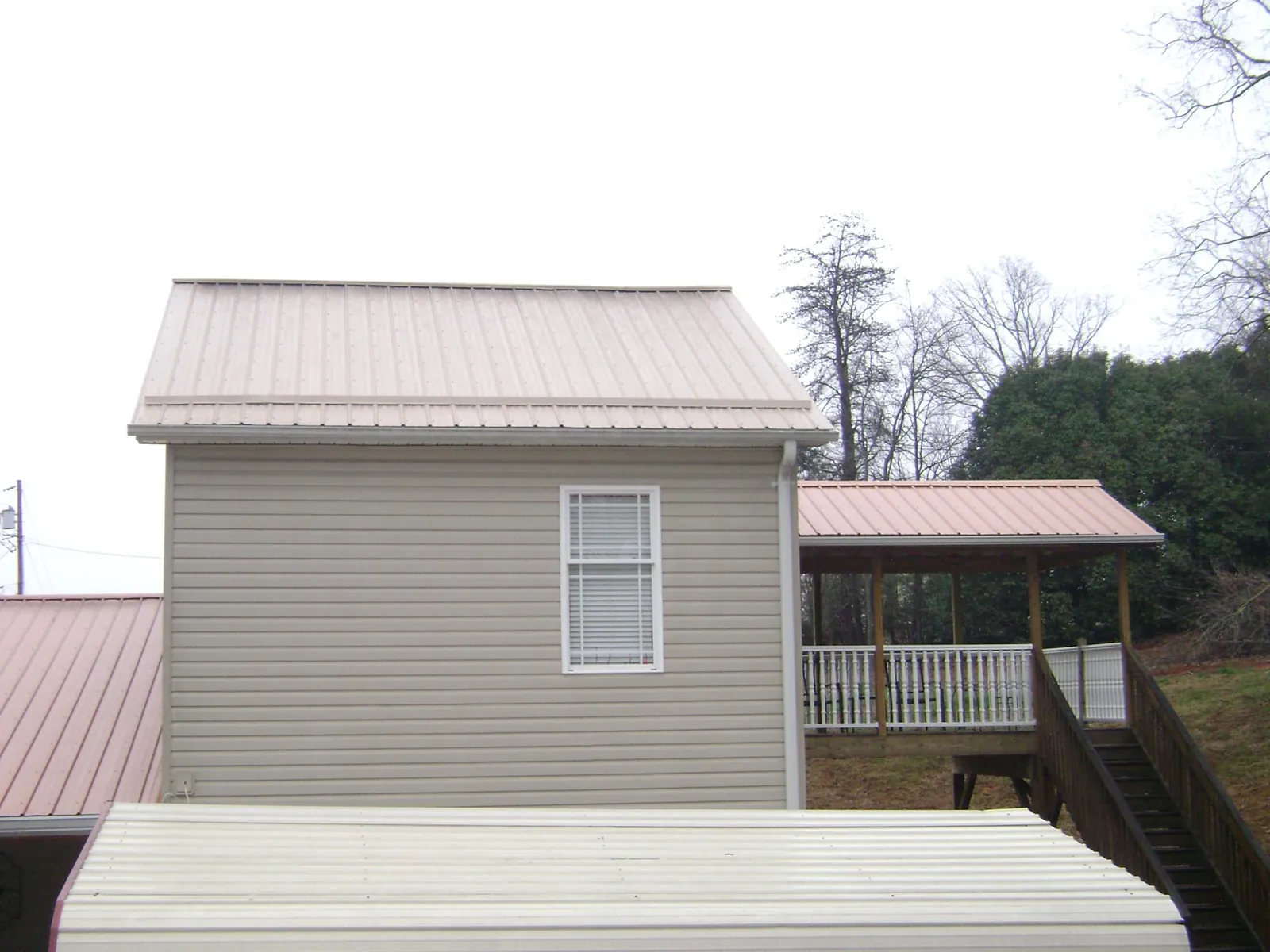 Tan metal roofs on a two story addition and attached porch, from a Roof Replacement job in Medinah