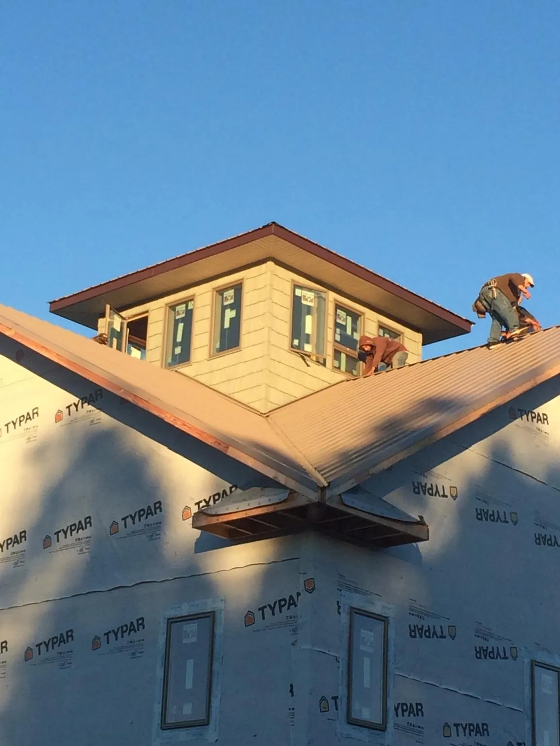 Roofers working around a rooftop cupola on a new metal roof at sunset — Roof Waterproofing in Medinah by Roofing Brothers